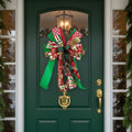 A decorative Christmas gift bow made from multiple patterned ribbons, including red and green striped fabric, white fabric with red floral motifs, red-and-white plaid, green ribbon, and a gold glitter accent, photographed against a plain white background.
