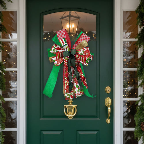 A decorative Christmas gift bow made from multiple patterned ribbons, including red and green striped fabric, white fabric with red floral motifs, red-and-white plaid, green ribbon, and a gold glitter accent, photographed against a plain white background.